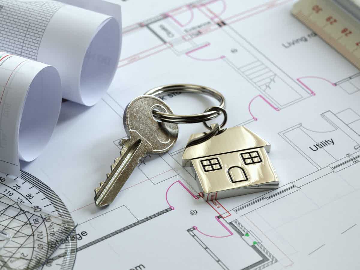 Small house key fob with key on architect's drawings