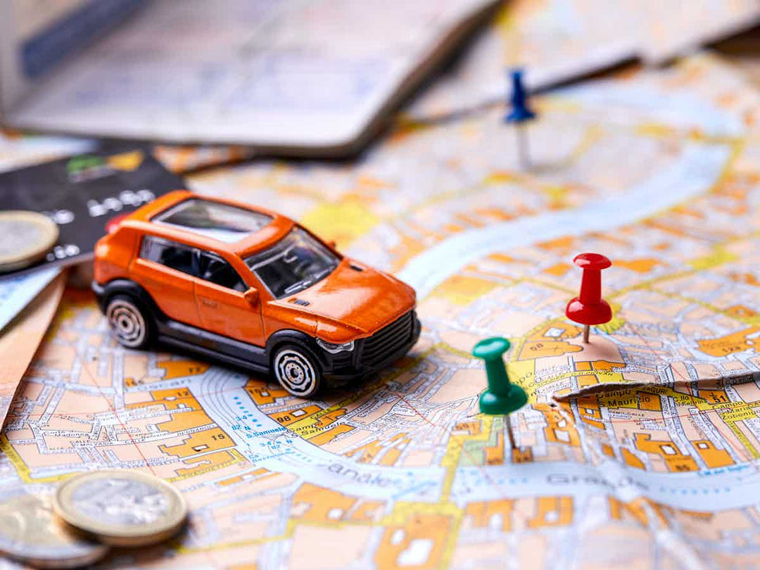 Orange model car on a map with differently coloured pins in the map